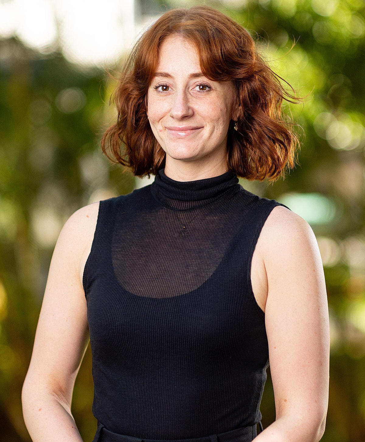 Woman smiling in a black sleeveless top.