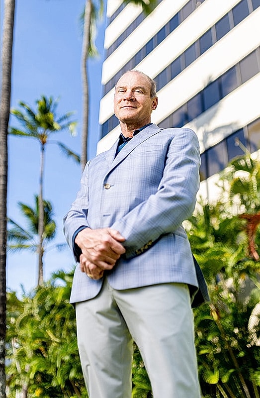 Man in suit against tropical background.