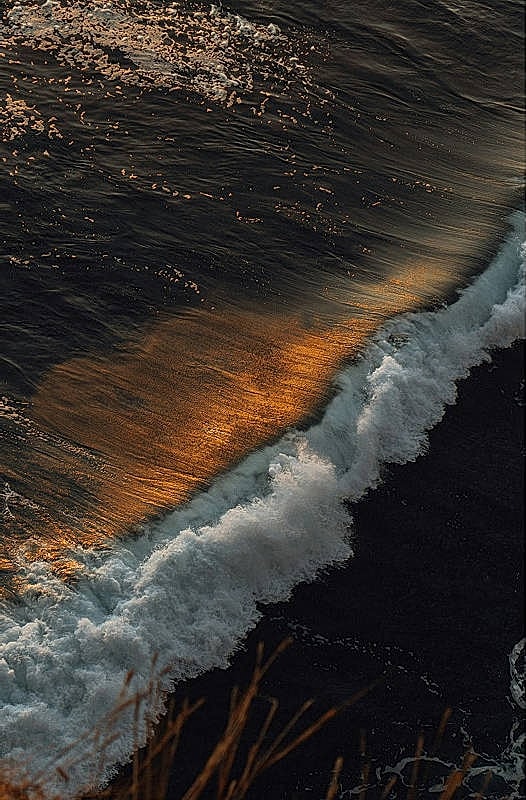 Waves and golden reflections on dark water.
