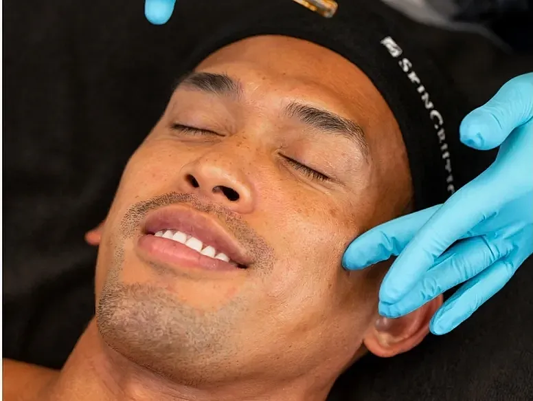 Facial treatment with gloved hands on client.