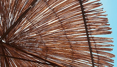 Straw umbrella against clear blue sky.