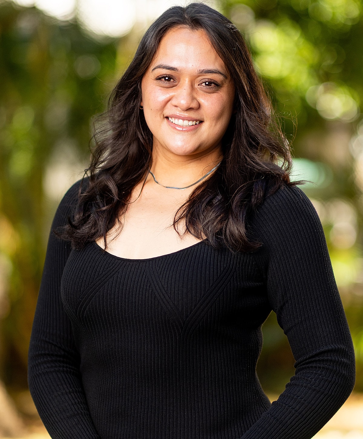 Smiling woman in a black sweater outdoors.