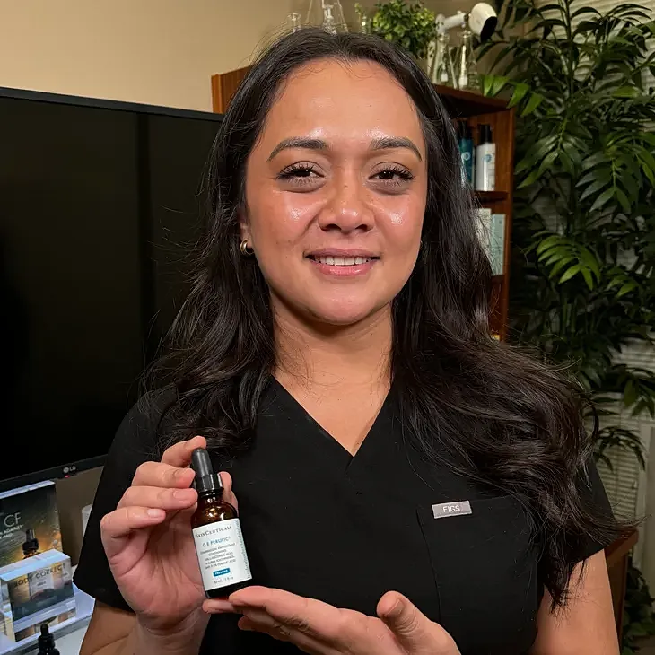 Woman holding skincare serum in professional setting.