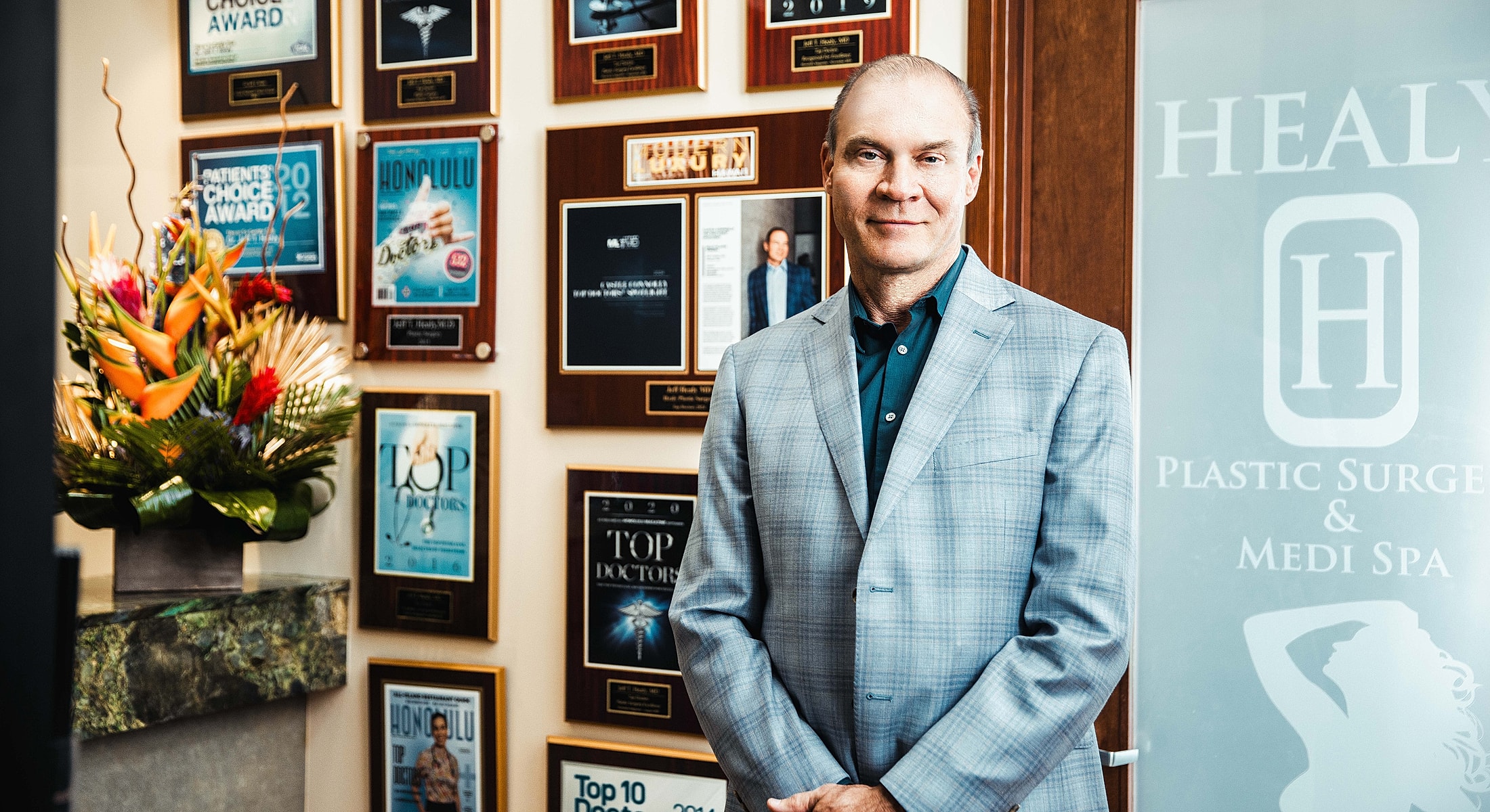 Plastic surgeon in office with award plaques.