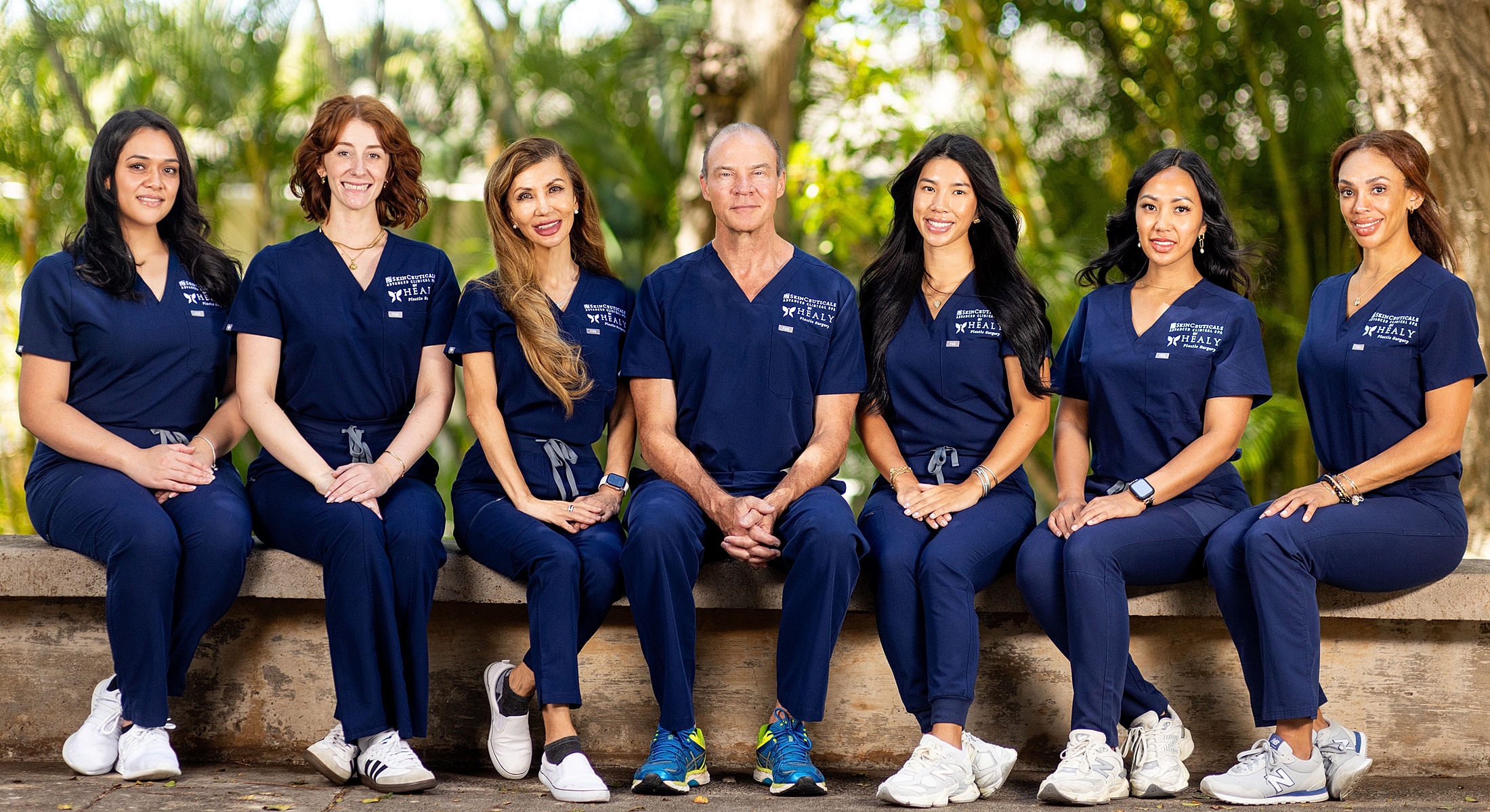 Medical team posing outdoors in navy scrubs.