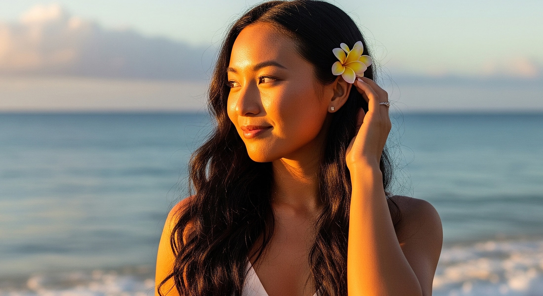 Woman with flower by ocean at sunset.