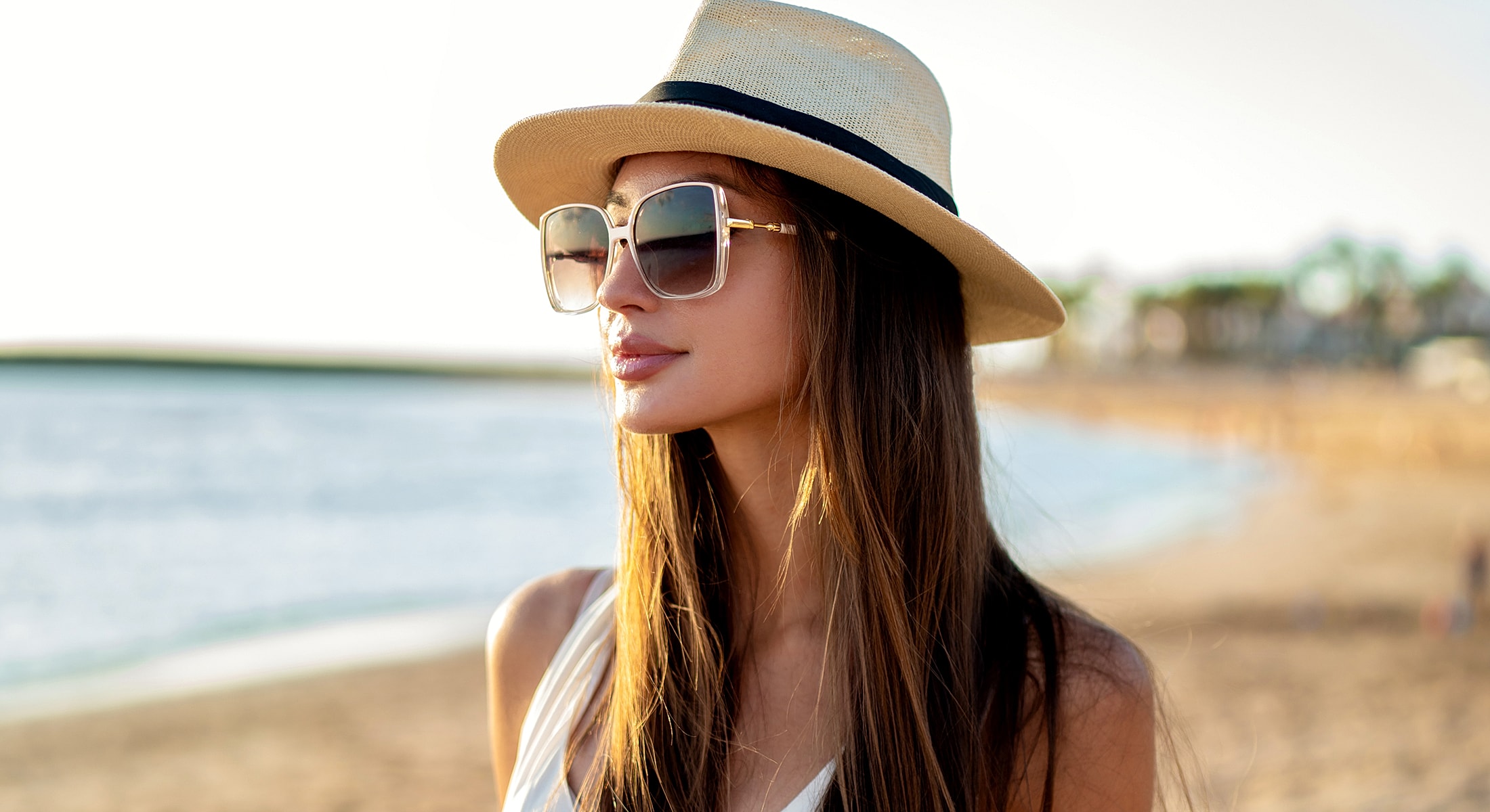 Woman in hat and sunglasses on beach.